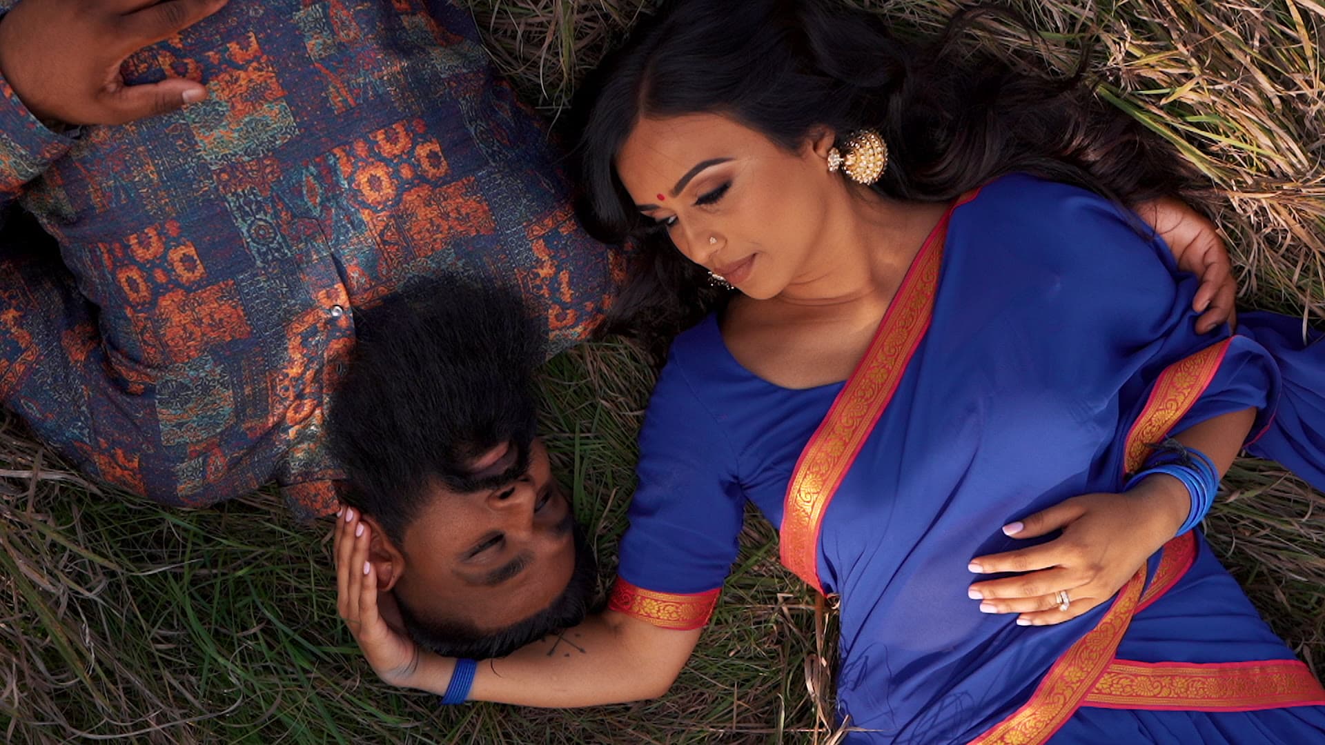 A bride and groom lying together in long grass, photographed from above